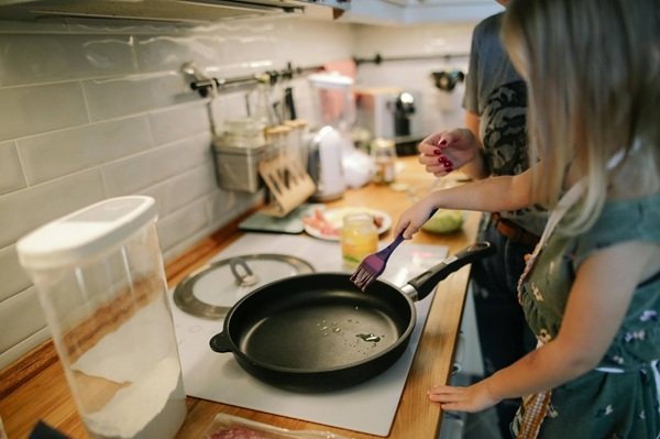 mother helping young daughter cook on stovetop