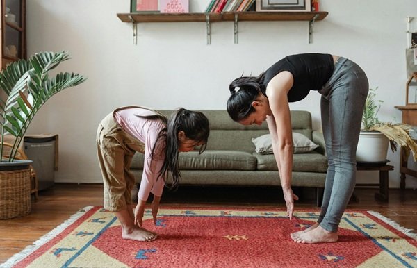 Woman and daughter Stretching Their Body in living room